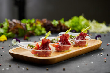 Appetizer from dry cured ham, prosciutto slices on a dark background. Photo for restaurant menu