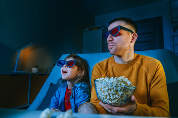 Father and daughter watching movie at home using 3D eye glasses