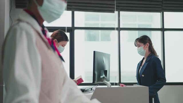 Asian airline passengers wear face masks at check-in at the airport. Women at the counter taking passport for verification. New normal, Illness Prevention, Covid-19 concept