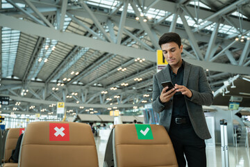 Portrait of young Elegant businessman using mobile phone app check-in boarding pass in airport.Handsome business professional man wearing suit texting smartphone inside office building or terminal