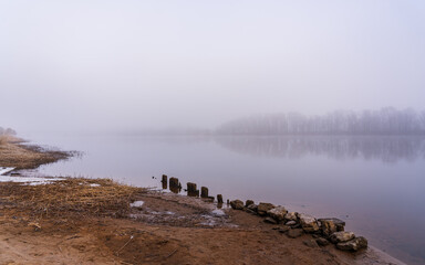 A foggy morning near the river. A row of rocks along the river.