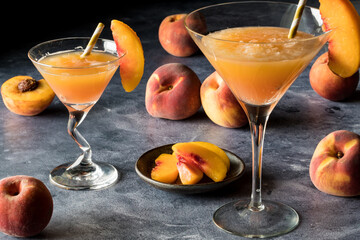Peach Bellinis garnished with slices of peach, against a dark background.