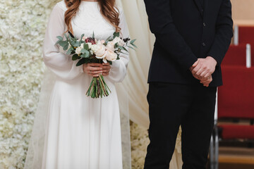 wedding day. bride in long white dress with bouquet of flowers and groom in black suit on wedding ceremony