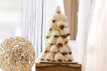 fresh strawberry covered by white chocolate designed as a pyramid, decoration of wedding party table