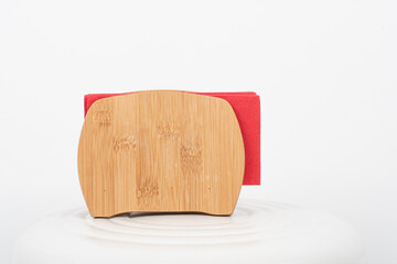 Bamboo holder is holding red napkins on white table and white background. Serving  concept.