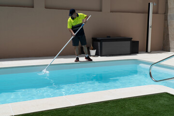 Operator cleaning a swimming pool with a butterfly trap