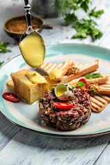 French cuisine, beef steak tartare with raw quail egg yolk, capers, pickled cucumber with bread...