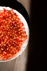Ripe pomegranate seeds on a plate. Fresh pomegranate fruit. On a grey background, top view
