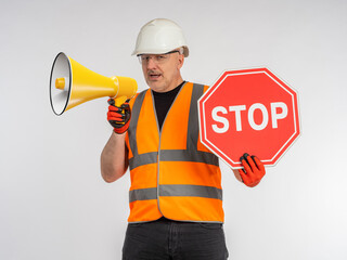 Man in road worker's uniform. Builder with loudspeaker. Road worker shows stop sign. Portrait of...