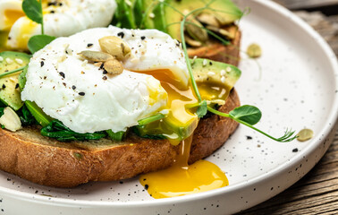 Poached egg on on bread with spinach, avocado and pumpkin seeds, Healthy food, keto diet, diet lunch concept. Top view