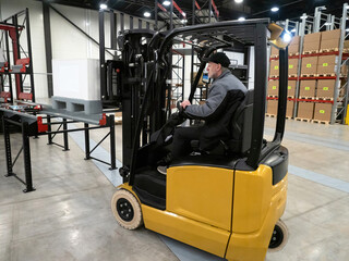 Forklift truck. Transportation for flight. Man drives forklift truck. Lifting knee with special technique. Forklift truck in warehouse with boxes. Adult man works as loader. Warehouse worker career