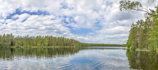 sky and white clouds reflect in forest lake