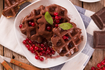 Waffles with chocolate topping, red currant and hazelnuts.