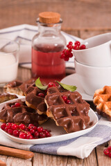 Waffles with chocolate topping, red currant and hazelnuts.