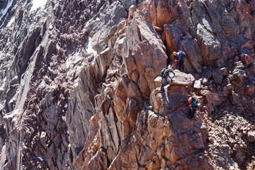 group of mountaineers are climbing on the stone rock with the rope