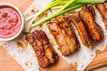 skewers of pork ribs with tomato sauce and green onion on the board top view macro close up