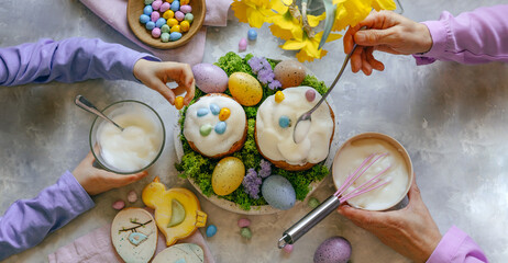 Grandmother and granddaughter decorating Easter cakes with chocolate eggs