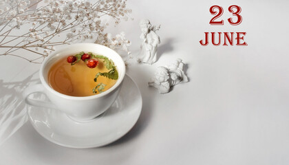 calendar date on light background with a porcelain cup of green tea, white gypsophila and angels with copy space. June 23 is the twenty-third  day of the month