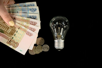 The concept of the cost of electricity. Electric lamp and money of russian rubles
