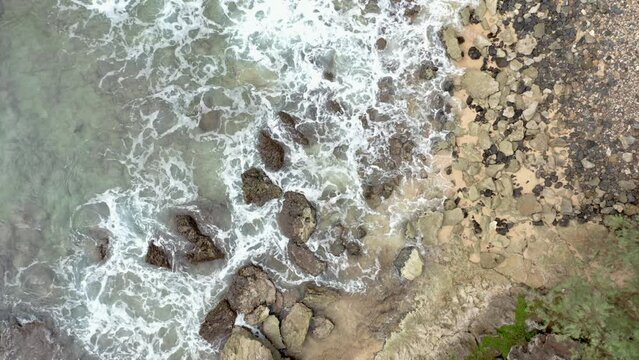Waves crashing onto the rocks at shipwreck beach kauai hawaii aerial overhead view, motion background