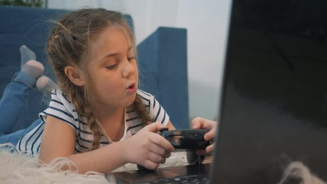 People playing video games. Happy cute kid gamer playing video game. child has fun at home alone. child gamer controls joystick while playing game on laptop monitor.