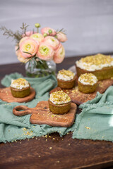 Pistazienkuchen und Cupcakes mit Frosting, Kaffeetisch Frühling mit Kuchen und Blumenstrauß