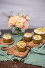 Pistazienkuchen und Cupcakes mit Frosting, Kaffeetisch Frühling mit Kuchen und Blumenstrauß