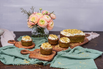 Pistazienkuchen und Cupcakes mit Frosting, Kaffeetisch Frühling mit Kuchen und Blumenstrauß