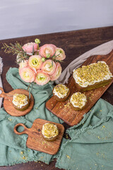 Obraz na płótnie Canvas Pistazienkuchen und Cupcakes mit Frosting, Kaffeetisch Frühling mit Kuchen und Blumenstrauß