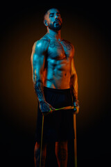 Fototapeta na wymiar Strong and muscular man posing in the studio with colored lights