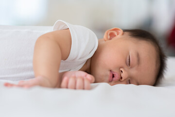 Happy asian newborn baby lying sleeps on a white bed comfortable and safety.Cute Asian newborn sleeping and napping at warmth place deep sleep and fresh breathing.Newborn Baby Sleep concept