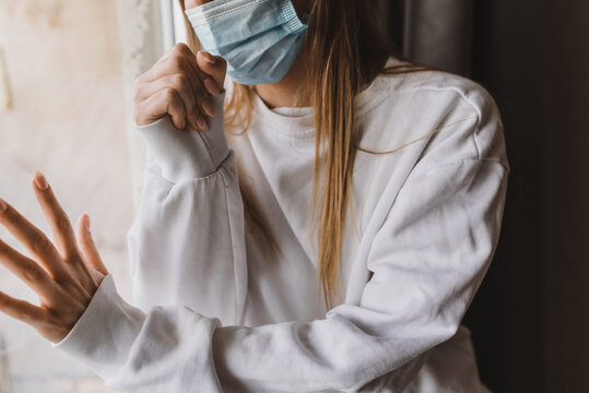 woman  near the window in the medical mask and coughing. Self isolation and quarantine