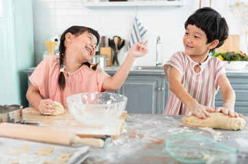 Happy asian family funny kids are preparing the dough, bake cookies in the kitchen.