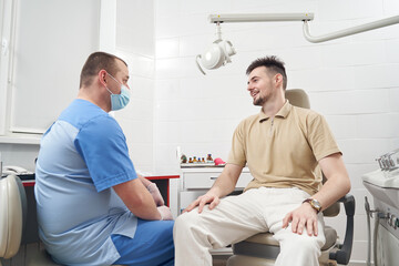 Obraz premium Jolly man visiting doctor office and communicating with him