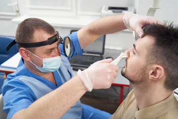 Fototapeta premium Man with runny nose visiting otorhinolaryngologist office