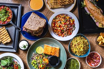 Assorted food set on table, Salmon with broccoli, salad, club sandwich, salad with quinoa, tartar from beef