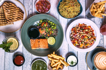 Assorted food set on table, Salmon with broccoli, salad, club sandwich, salad with quinoa, tartar from beef