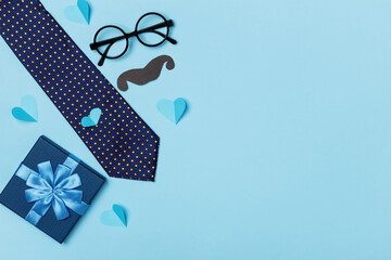 Fathers day concept. Gift tie glasses mustache hearts on a blue background. Top view flat lay copy space
