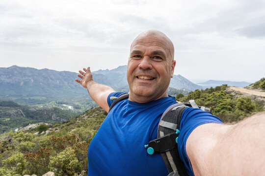An adventurous hiker man takes a selfie in a natural environment.