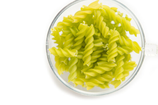 Close-up background of Fusille and Rotini in a glass bowl on white. pasta colorata