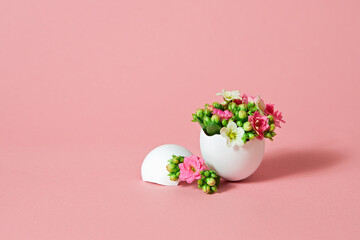 White Easter egg with beautiful spring flowers on pink background.