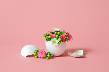 White Easter egg with beautiful spring flowers on pink background.