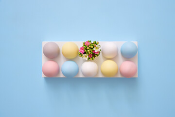 Colorful Easter eggs with spring flowers on blue background.