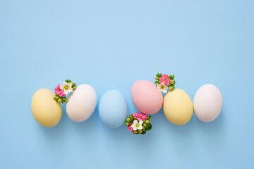 Colorful Easter eggs with spring flowers on blue background.