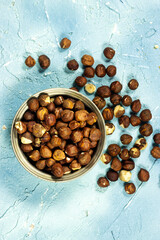 Hazelnuts in a metal bowl on blue  background