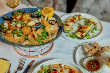 Assorted view of dinner table with delicious food set  for two, seafood,Salmon with broccoli, salad, club sandwich, salad with quinoa, tartar from beef