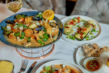 Assorted view of dinner table with delicious food set  for two, seafood,Salmon with broccoli, salad, club sandwich, salad with quinoa, tartar from beef