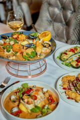Assorted view of dinner table with delicious food set  for two, seafood,Salmon with broccoli, salad, club sandwich, salad with quinoa, tartar from beef