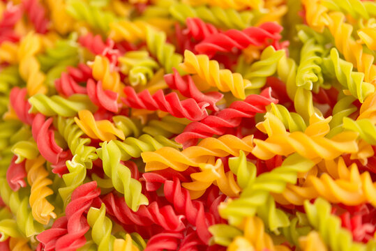 Close-up background of Fusille and Rotini in a glass bowl on white. pasta colorata