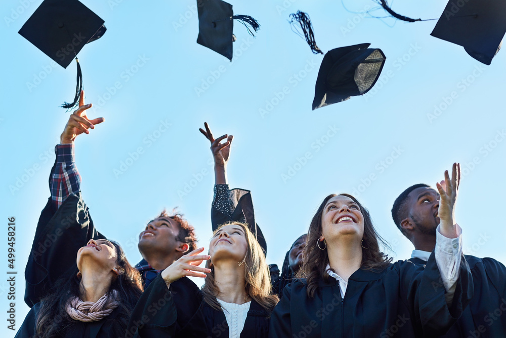 Poster we did it. shot of a group of students throwing their hats in the air on graduation day.